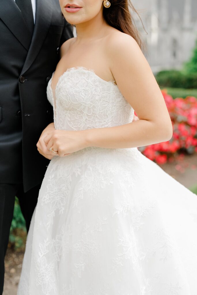 A bride in a lace ballgown stands beside her partner, highlighting the intricate texture and silhouette of her wedding dress. Classic bridal style for a 620 Loft and Garden wedding ceremony.