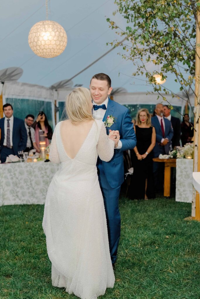 Bride and groom sharing their first dance together during a Vermont wedding reception, surrounded by loved ones.