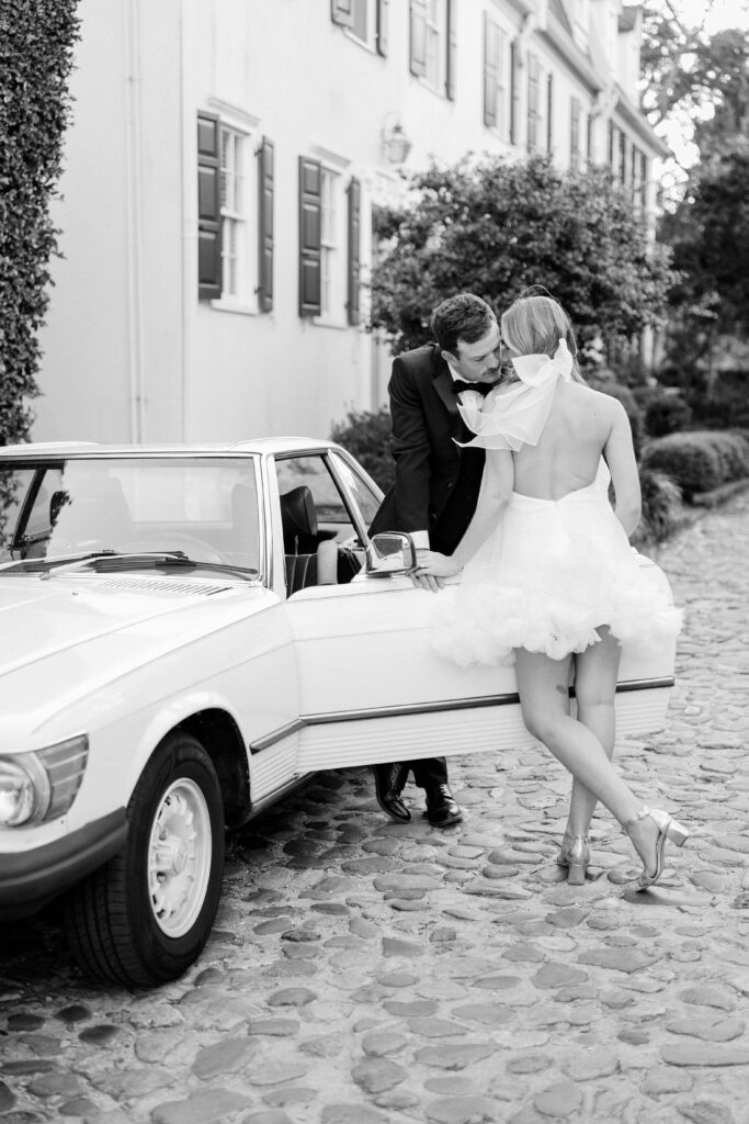 Black and white intimate detail photo of groom laughing with bride's bow dress visible — dreamy downtown Charleston SC couples session
