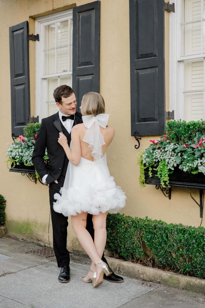  Bride and groom standing close together against a sun-drenched yellow stucco wall in the historic district of downtown Charleston SC — romantic couples session by Felisha Lees Photography
