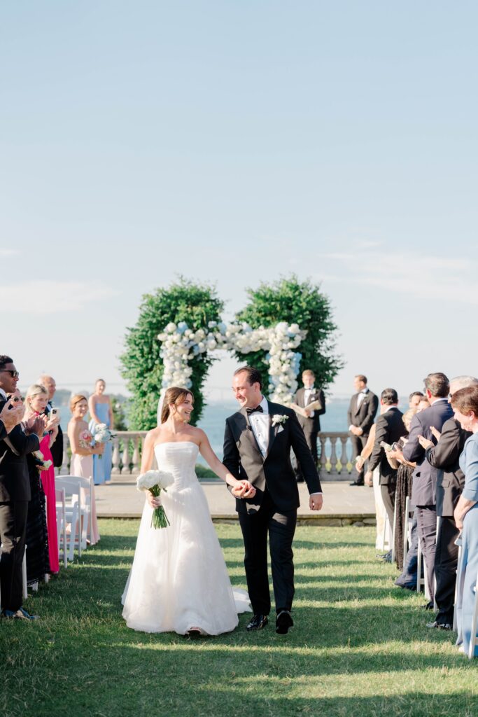 The newlyweds walk back down the aisle surrounded by cheering family and friends after their oceanfront ceremony. Ceremony photography is one of the highlights of a Castle Hill Inn wedding celebration.