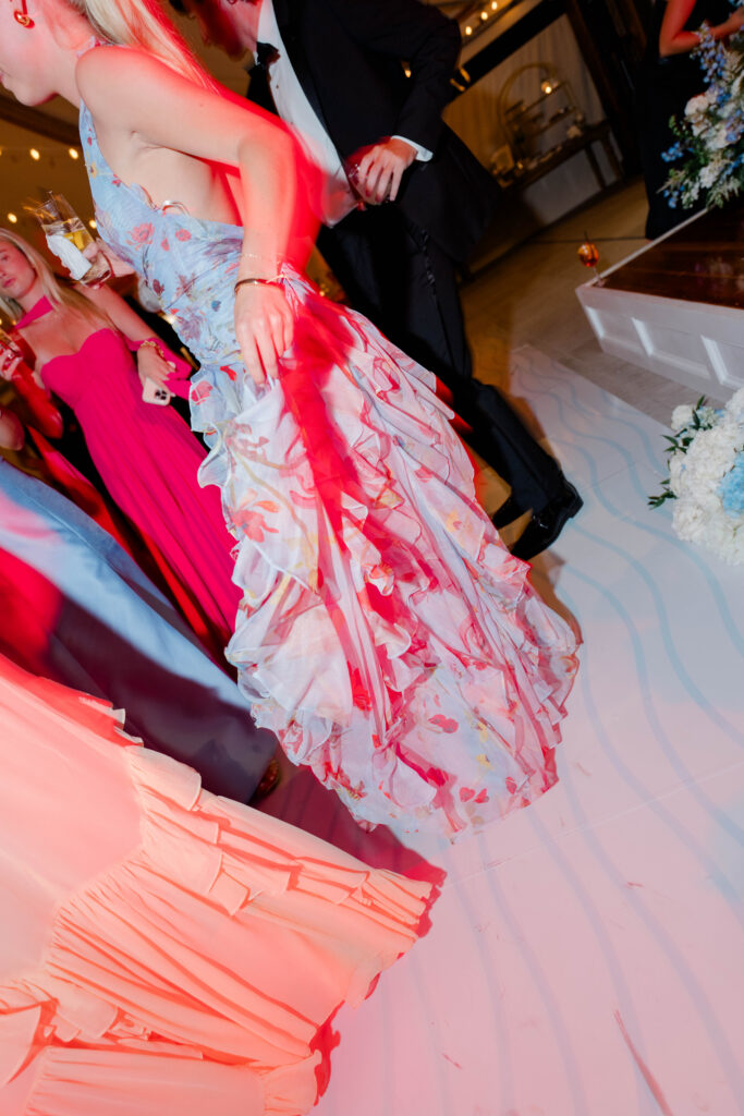 A guest twirls across the dance floor as colorful reception lighting captures the energy of the evening celebration. Editorial reception photography from a Castle Hill Inn wedding.