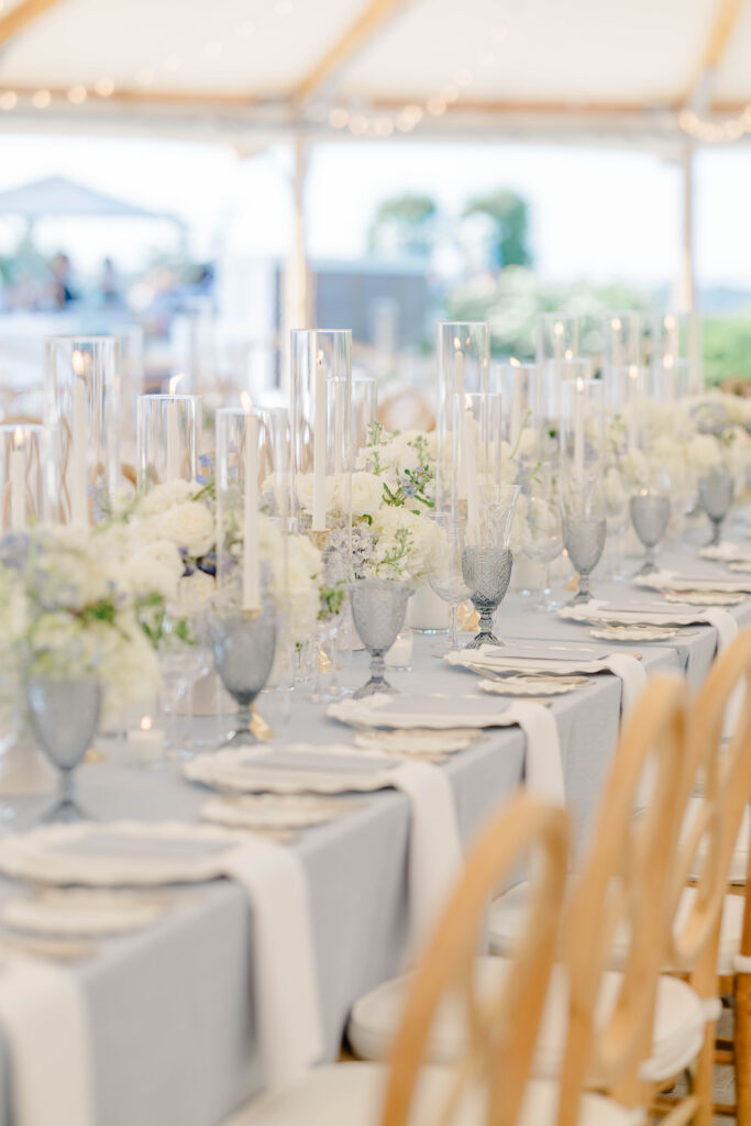 Elegant reception tablescape with champagne flutes, candlelight, and soft neutral florals beneath a tent, reflecting timeless New England wedding style.