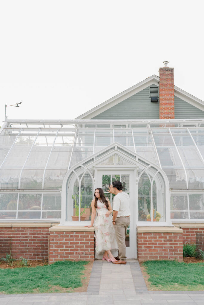 The couple stands together in front of the greenhouse entrance, using its clean architectural lines as a timeless backdrop. A favorite portrait location for Elizabeth Park photography.