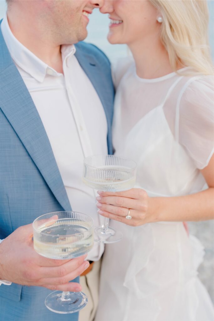 Molly and Anthony smiling together while holding champagne glasses during their Rhode Island engagement session.